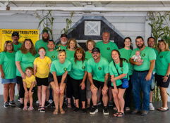 A lively group in matching green shirts celebrates indoors, showcasing unity, joy, and a family-friendly atmosphere.