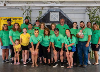 A lively group in matching green shirts celebrates indoors, showcasing unity, joy, and a family-friendly atmosphere.