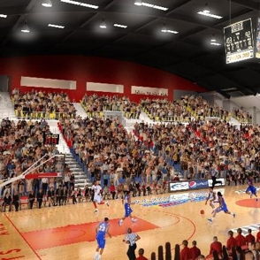 A vibrant basketball stadium filled with fans watching an exciting game, illuminated by bright lights and a scoreboard overhead.