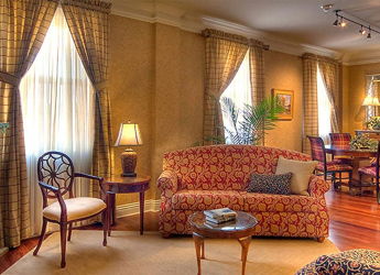 Inviting living room with plush seating, warm colors, large windows, tasteful decor, and a cozy fireplace.