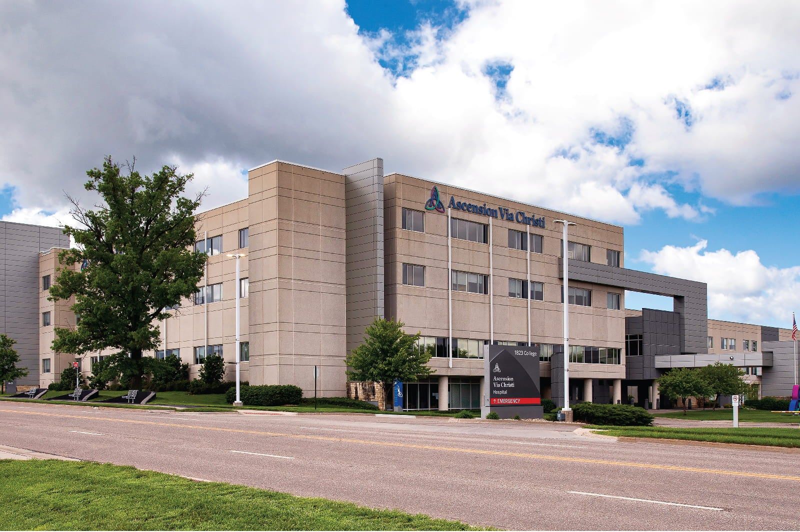 Modern multi-story medical facility with large windows, surrounded by lawns and trees, evoking openness, comfort, and professionalism.