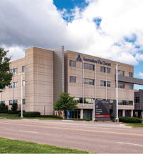 Modern multi-story medical facility with large windows, surrounded by lawns and trees, evoking openness, comfort, and professionalism.