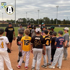 Youth baseball team in huddle, focused on coach, on a diamond field, exuding teamwork and anticipation for their game.