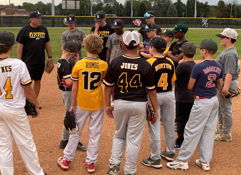 Youth baseball team in huddle, focused on coach, on a diamond field, exuding teamwork and anticipation for their game.