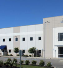Modern industrial building with sleek design, large windows, surrounded by greenery, conveying professionalism and optimism.