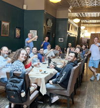 A lively restaurant gathering with smiling people raising glasses, exuding joy, camaraderie, and a celebratory atmosphere.