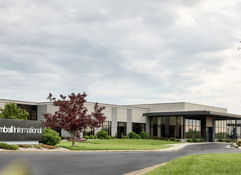 Modern corporate building with landscaping, American flag, evokes stability, professionalism, calmness, and productivity.