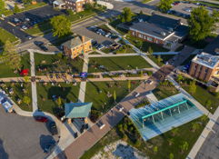 Aerial view of a vibrant community area with green spaces, pathways, and people, reflecting joy, serenity, and activity.