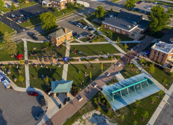 Aerial view of a vibrant community area with green spaces, pathways, and people, reflecting joy, serenity, and activity.