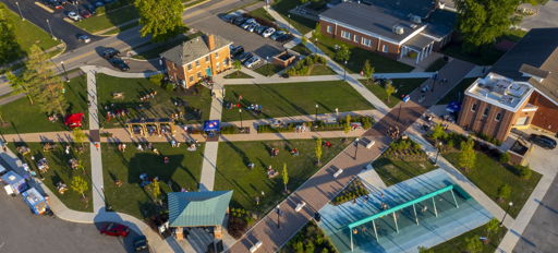 Aerial view of a vibrant community area with green spaces, pathways, and people, reflecting joy, serenity, and activity.