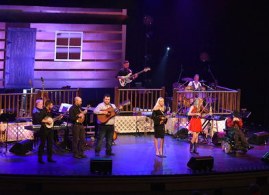 Lively stage performance with musicians in a rustic backdrop, evoking joy and community through vibrant music and engagement.