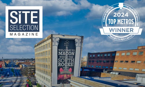 Cityscape of Macon featuring "WELCOME TO MACON" mural, bright sky, and "2024 TOP METROS WINNER" badge, exuding vibrancy and pride.