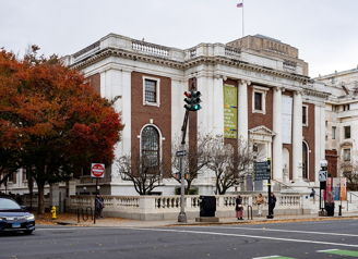 Grand building with red brick and white columns, autumn trees, overcast sky; evokes nostalgia and appreciation for history.