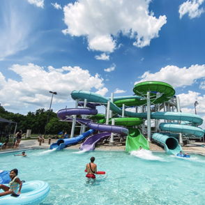 Vibrant water park with colorful slides, families enjoying the pool, under a sunny sky, evoking joy and summer fun.