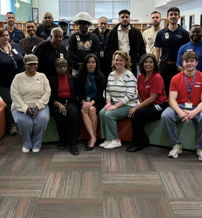 A diverse group of individuals smiles and engages in a welcoming library, promoting unity, camaraderie, and positivity.