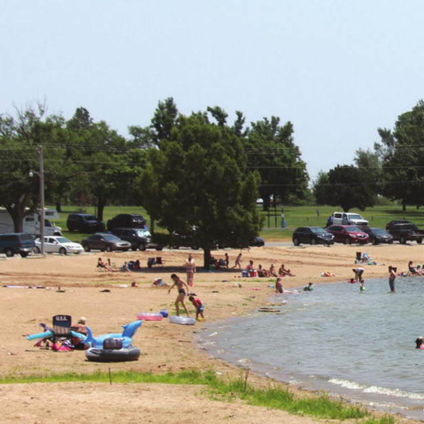 A lively beach scene shows people swimming, playing, and relaxing under sunny skies, evoking joy and community.