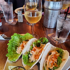 Lettuce-wrapped tacos with salad, green sauce, lime, and drinks, evoking a lively, relaxed dining experience.