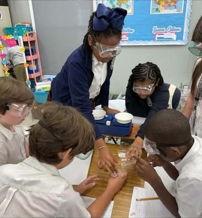 Students in safety goggles collaborate on a science experiment, showing curiosity, teamwork, and excitement in a classroom.