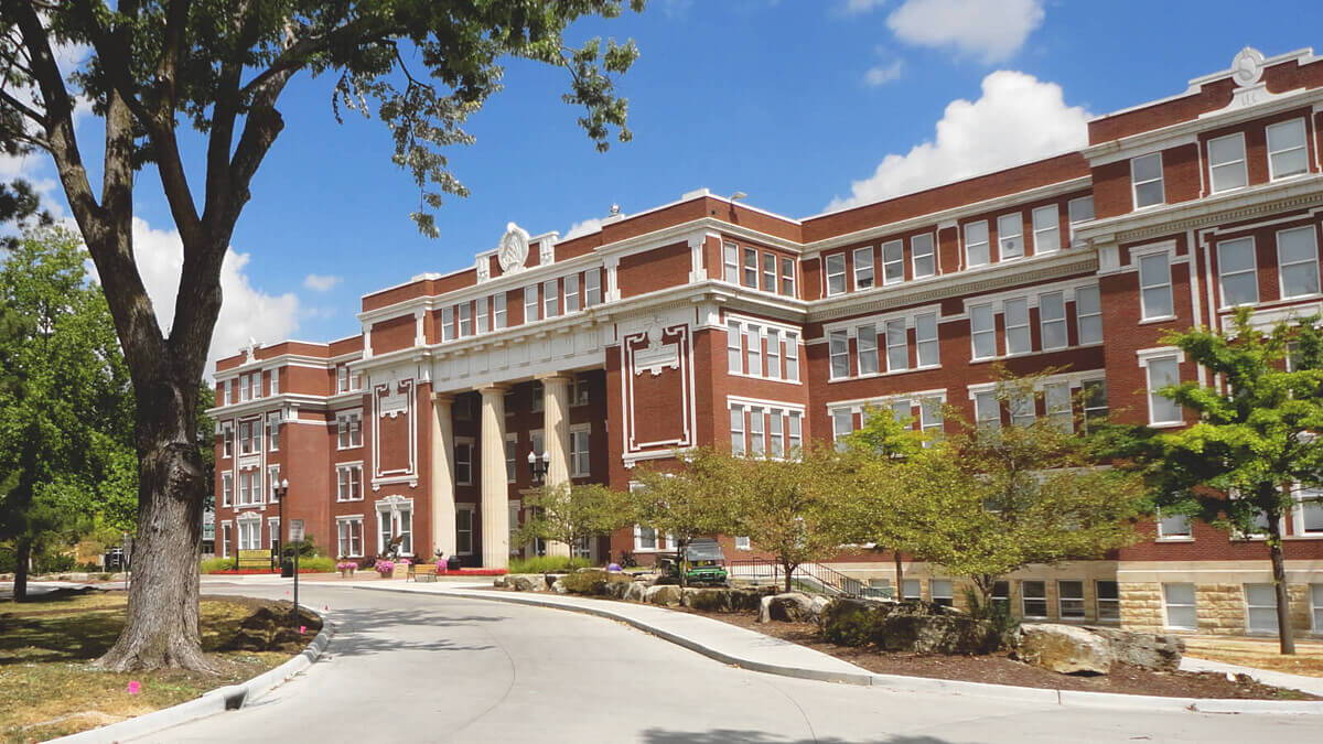 A stately brick academic building with classic architecture, surrounded by landscaped grounds, evokes inspiration and warmth.