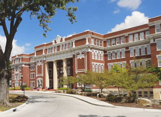 A stately brick academic building with classic architecture, surrounded by landscaped grounds, evokes inspiration and warmth.