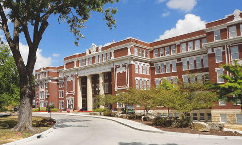 A stately brick academic building with classic architecture, surrounded by landscaped grounds, evokes inspiration and warmth.