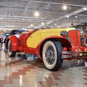 Vintage red and yellow convertible car in a museum, showcasing classic design and evoking nostalgia and admiration.