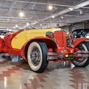 Vintage red and yellow convertible car in a museum, showcasing classic design and evoking nostalgia and admiration.