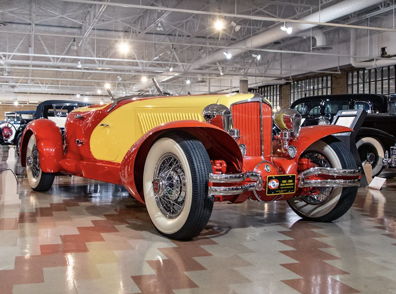 Vintage red and yellow convertible car in a museum, showcasing classic design and evoking nostalgia and admiration.