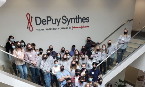 A vibrant office gathering shows unity and professionalism, with many wearing masks, highlighting health awareness and positivity.