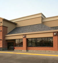 A welcoming retail store with brick and beige architecture, large windows, and outdoor seating, inviting for a relaxing shopping experience.