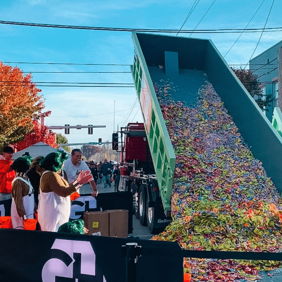 A truck unloads colorful candy at a lively outdoor event, evoking joy and excitement among gathered spectators.