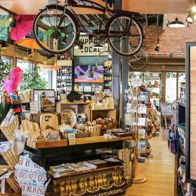 Charming store filled with goods, a whimsical hanging bicycle, and "GREETINGS FOLKS!" sign, evoking warmth and nostalgia.