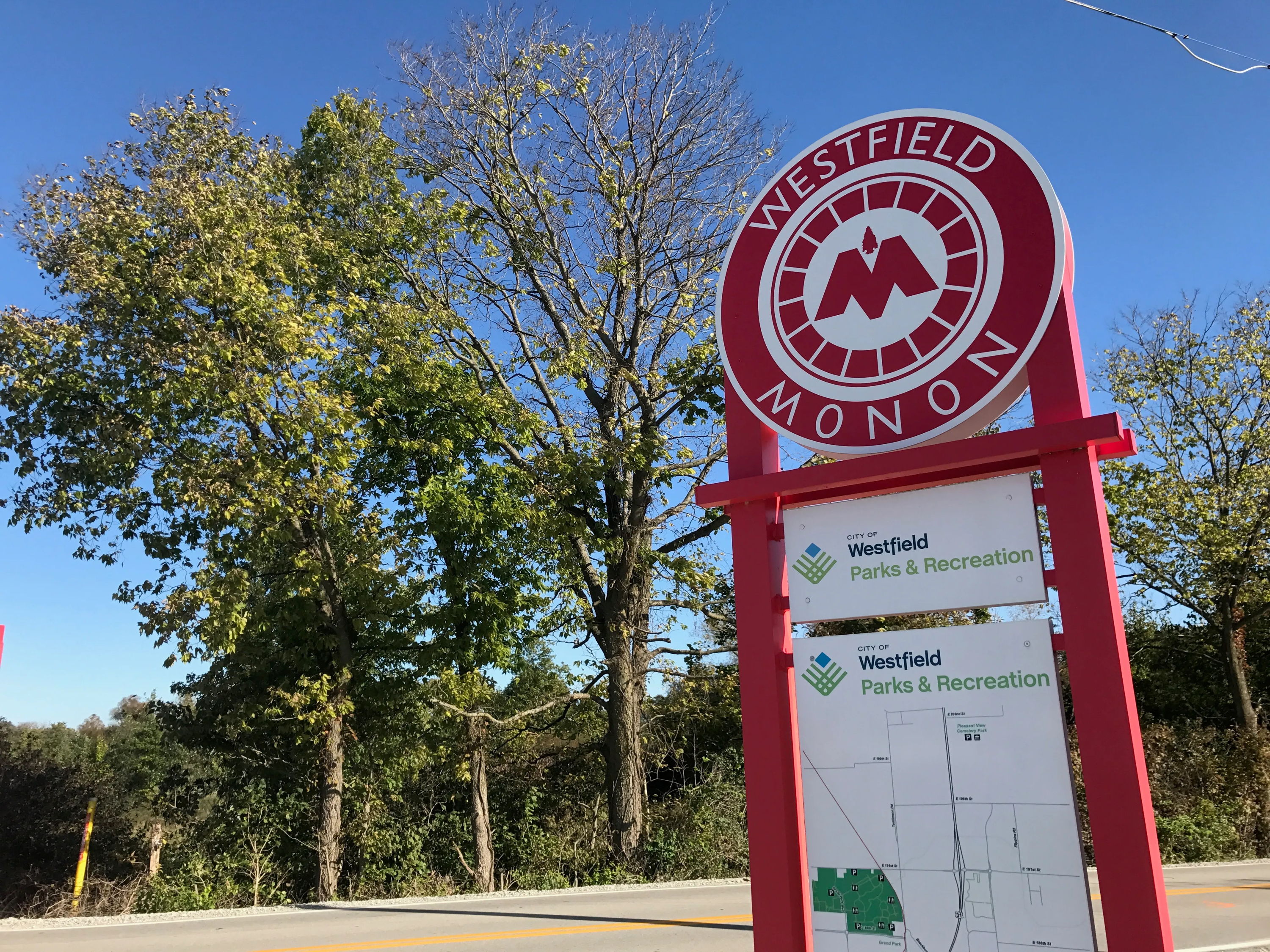 Colorful "Westfield Monon" sign with trees and clear skies, inviting outdoor adventure and community engagement.