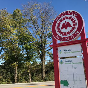 Colorful "Westfield Monon" sign with trees and clear skies, inviting outdoor adventure and community engagement.