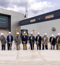 A group in hard hats on a construction site celebrates a groundbreaking, symbolizing excitement, collaboration, and progress.