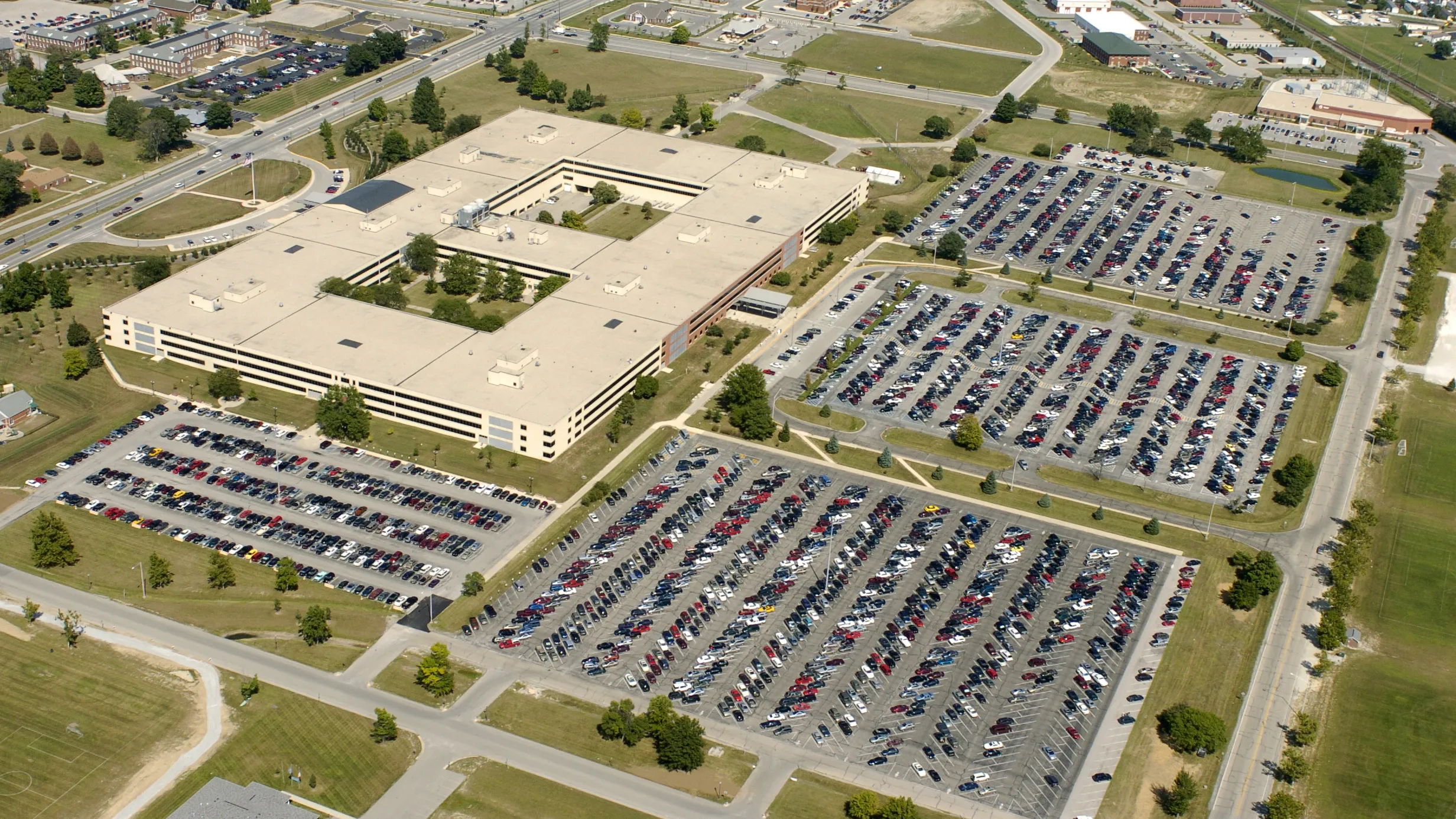 Aerial view of a busy parking area by a modern office building, showcasing organization and a sense of community.