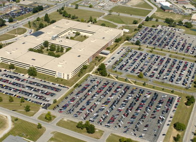 Aerial view of a busy parking area by a modern office building, showcasing organization and a sense of community.