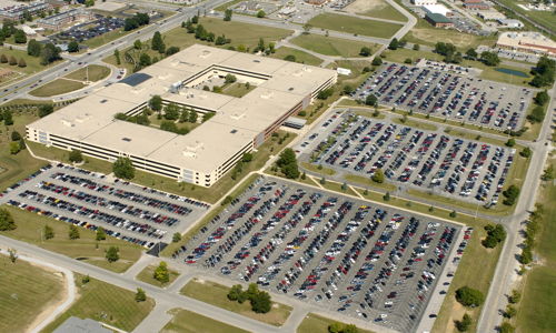 Aerial view of a busy parking area by a modern office building, showcasing organization and a sense of community.