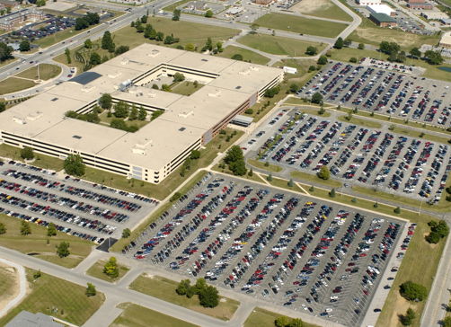 Aerial view of a busy parking area by a modern office building, showcasing organization and a sense of community.
