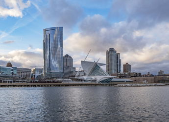 Modern skyline with sleek glass buildings by water, evoking serenity, majesty, nostalgia, and hopefulness under dynamic skies.