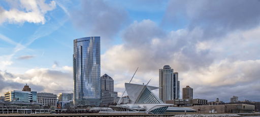 Modern skyline with sleek glass buildings by water, evoking serenity, majesty, nostalgia, and hopefulness under dynamic skies.