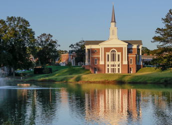A peaceful landscape with a church by a calm lake, surrounded by greenery and soft sunlight, evoking serenity and spirituality.