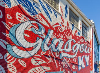 Vibrant mural on a brick wall, featuring "Glasgow" in bold colors, evoking creativity and community pride.