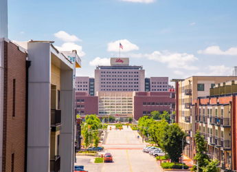 Bright urban street scene with modern buildings, a prominent flag-topped structure, and clear skies, evoking tranquility and positivity.