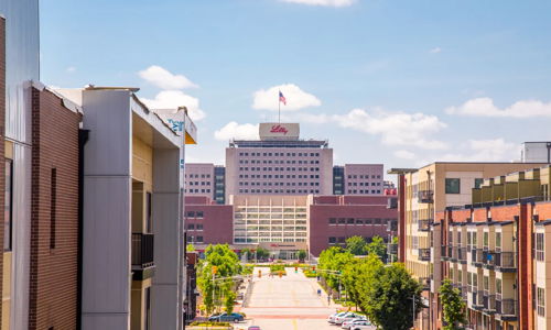 Bright urban street scene with modern buildings, a prominent flag-topped structure, and clear skies, evoking tranquility and positivity.