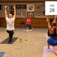 Group yoga class in a warm, inviting studio; participants practice poses, fostering calmness, community, focus, and joy.
