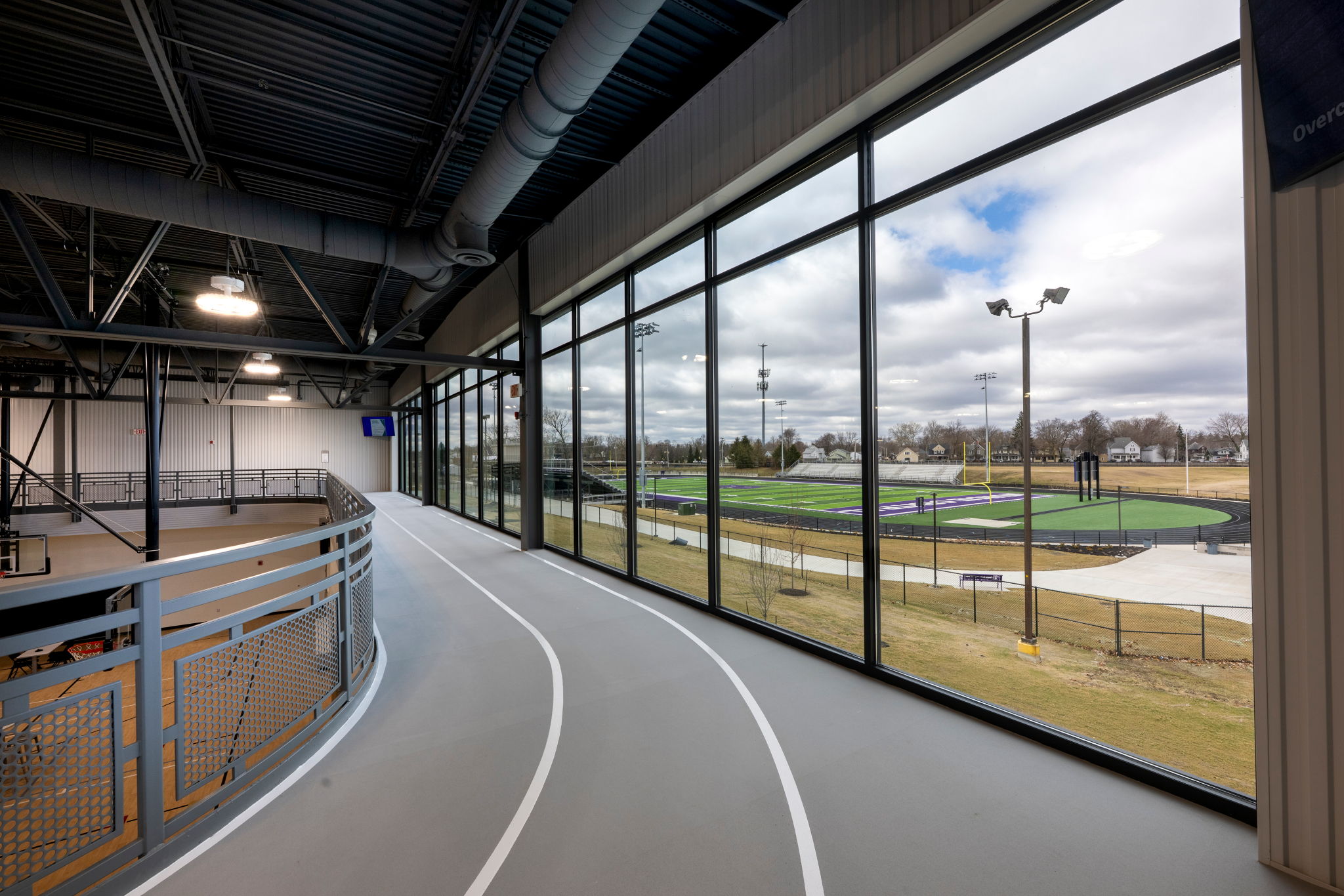 Modern indoor athletic facility with a curved track, large windows, and a blend of natural and artificial light, promoting energy and wellness.