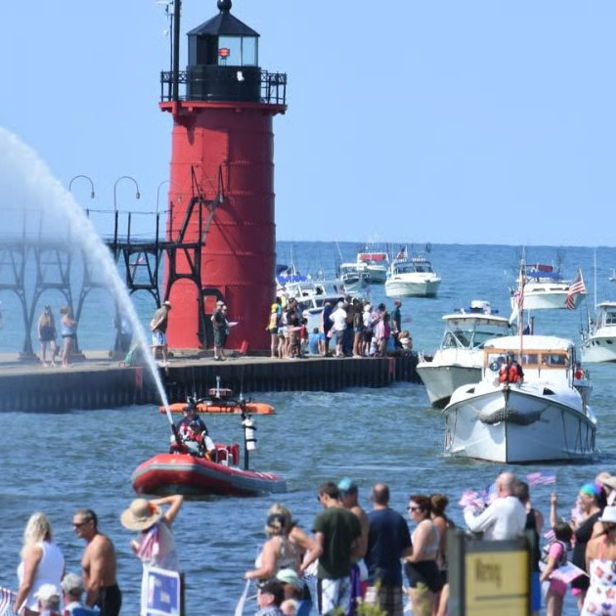 Vibrant summer waterfront scene with a red lighthouse, boats, people enjoying festivities, and a lively fountain spray.