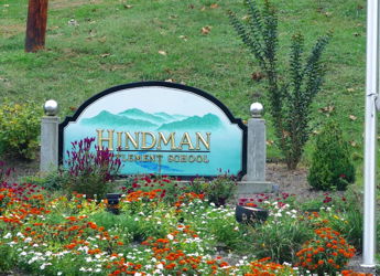 Sign for Hindman Elementary School amid vibrant flowers and mountains, creating a warm, inviting atmosphere.