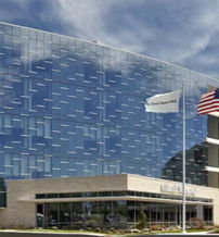 Modern building with glass façade, curved and angular design; reflects sky, suggesting professionalism and transparency.